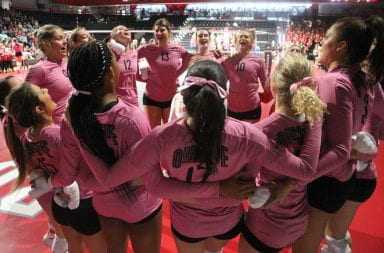 The Ohio State women's volleyball team standing in a circle getting pumped up before a game.