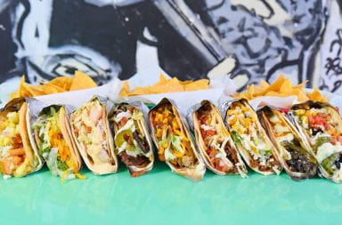 A line of tacos on a turquoise table