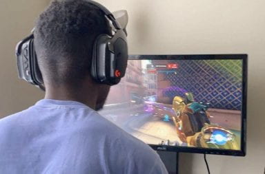 Justin Yancey has a gaming headset on as he plays Overwatch on his computer monitor.