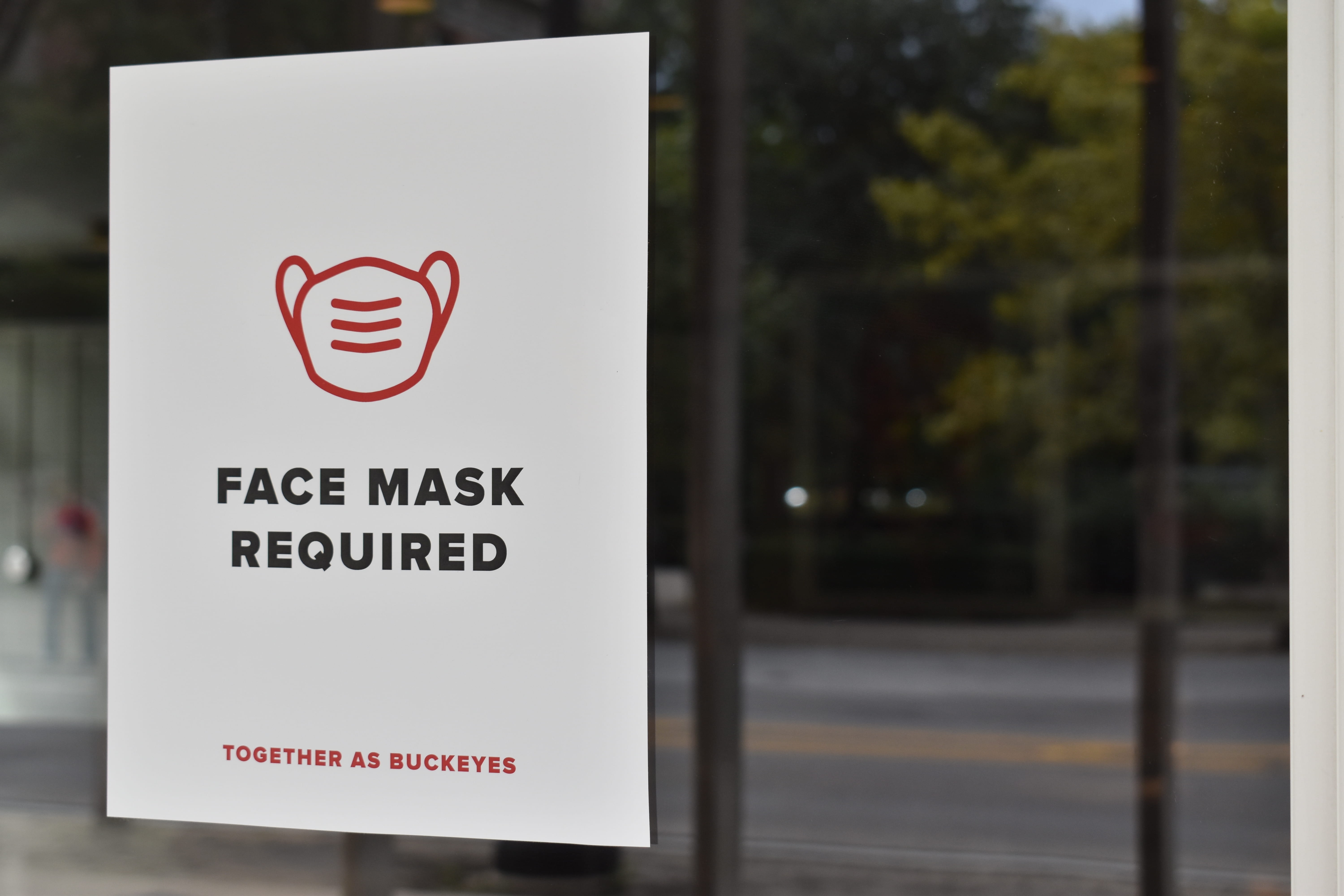 a face mask required sign posed on the doors of all of the hall buildings