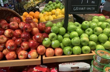 red and green apples line the table at the grocery store in the produce section