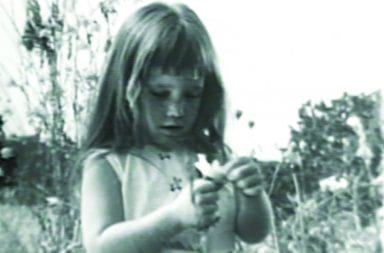 a little girl holding daisys in the field