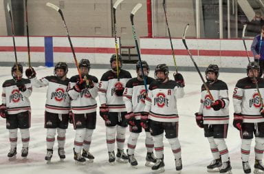 The Ohio State Women's Ice Hockey team raise their sticks in the air