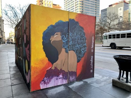A boarded up location features public art displaying African American celebratory art