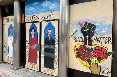 Boarded up windows and doors display works of public art memorializing the Black Lives Matter movement and victims of police violence.