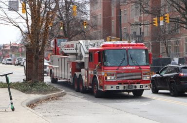 A red fire truck pulls through an intersection after blocking cars
