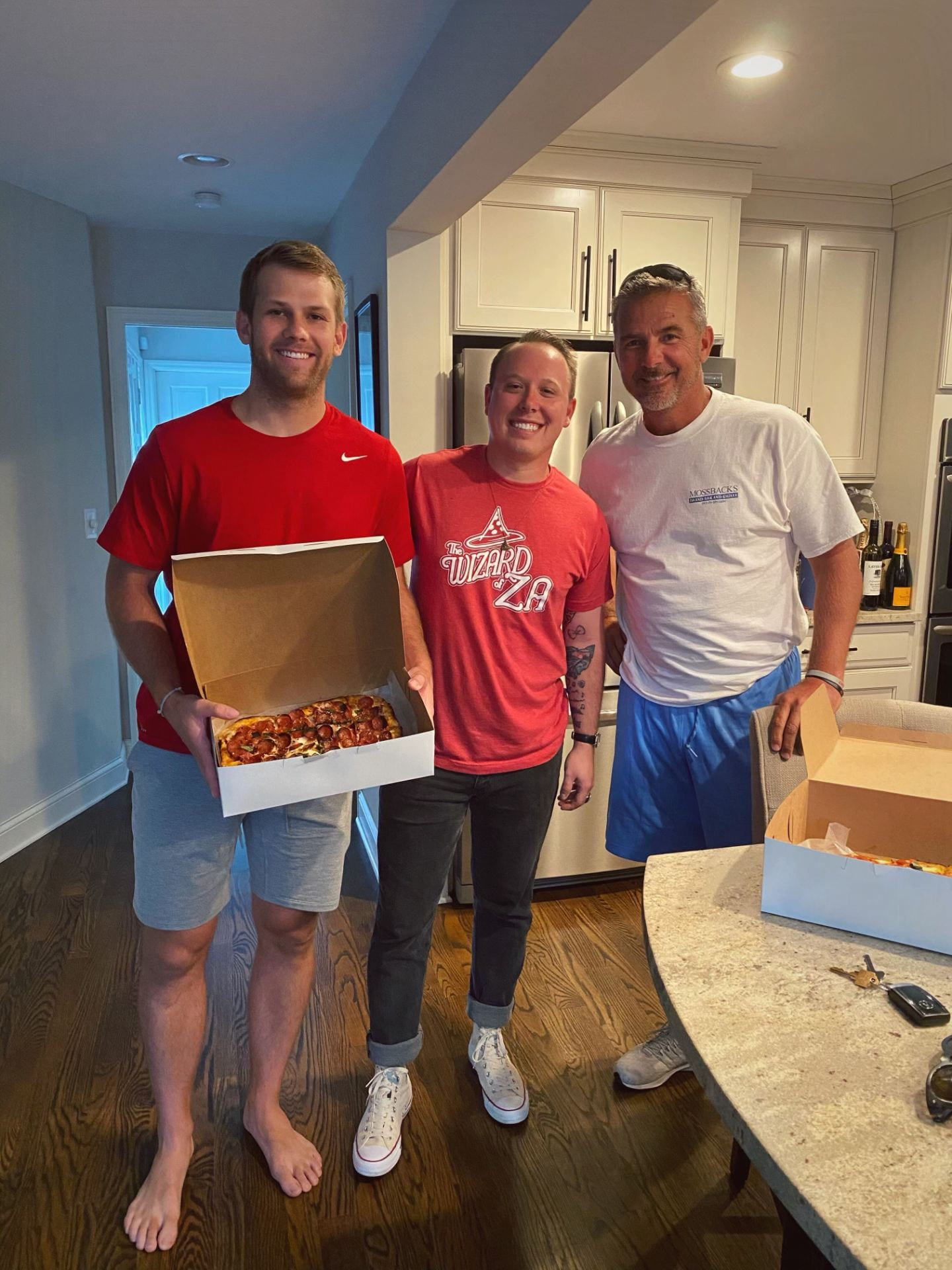 Tre uomini posano per una foto con una pizza