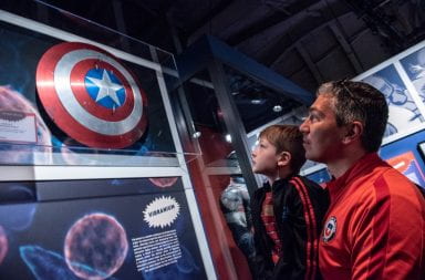 Father and son look at captain America Shiel at exhibit.