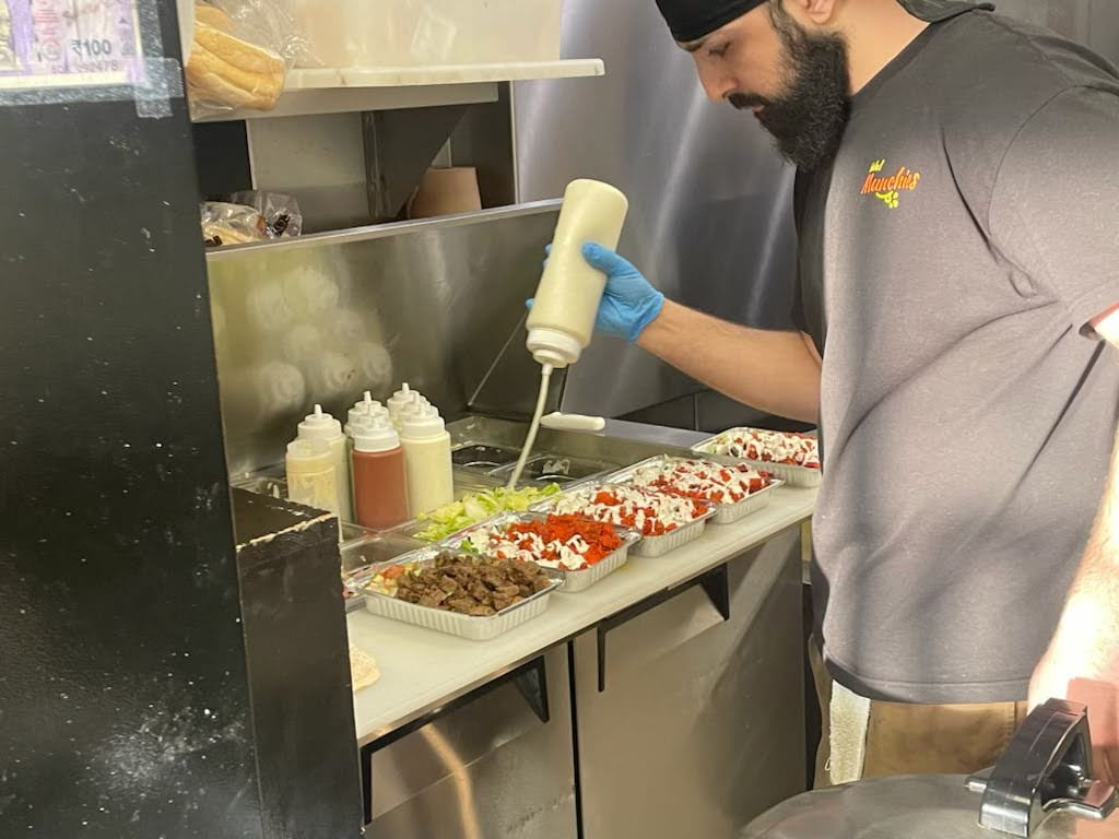 An employee at Halal Munchies drizzles white sauce over chicken and lamb platters on Feb. 28. Credit: Raghav Raj | Lantern Reporter