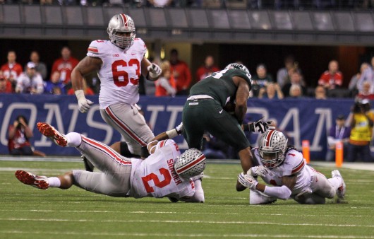Junior linebacker Ryan Shazier (2) and redshirt-junior cornerback Bradley Roby (1) make a tackle during the Big Ten Championship Game Dec. 7 in Indianapolis. OSU lost to Michigan State, 34-24. Credit: Shelby Lum / Photo editor