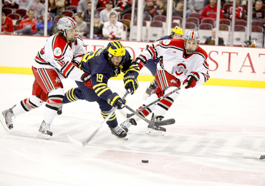 Freshman defenseman Drew Brevig (4) and junior forward Tanner Fritz (16) flank an opposing player during a game against Michigan Dec. 2 at the Schottenstein Center. OSU lost, 5-4. Credit: Kelly Roderick / For The Lantern