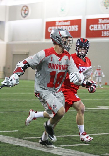 Then-senior attackman Logan Schuss (18) advances the ball during a game against Detroit Feb. 9 at the Woody Hayes Athletic Center. OSU won, 14-8. Credit: Shelby Lum / Photo editor