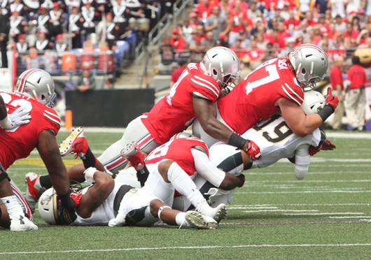 Sophomore defensive lineman Joey Bosa (97) leads a group of OSU players in tackling Navy quarterback Keenan Reynolds (19) during a game against the Midshipmen Aug. 30 at M&T Bank Stadium in Baltimore. OSU won, 34-17. Credit: Mark Batke / Photo editor