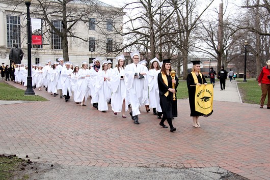 A chapter of the Mortar Board Society carries the “Golden Torch” for the Golden Torch Award across campus. Credit: Courtesy of LoLynn Giancola