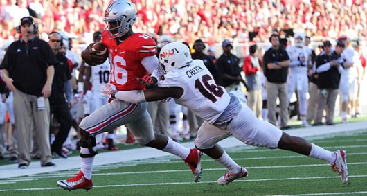 Redshirt sophomore quarterback J.T. Barrett (16) tries to shake off a tackler during a game against Northern Illinois on Sept. 19. OSU won 20-13. Credit: Samantha Hollingshead / Photo Editor