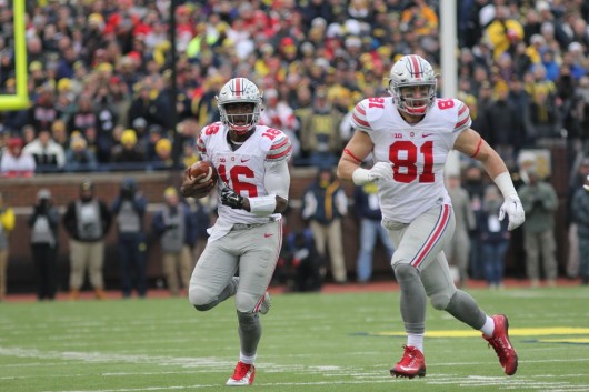 OSU redshirt sophomore J.T. Barrett (16) carries the ball while redshirt senior tight end Nick Vannett (81) looks for a defender to block during a game against Michigan on Nov. 28. OSU won, 42-13. Credit: Samantha Hollinshead | Photo Editor