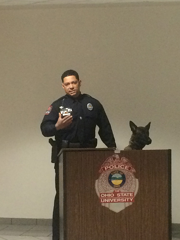University Police Officer Bryan Thompson speaks at the ceremony with K-9 Ena by his side. Credit: Aubrey Cornwell | Lantern Reporter 