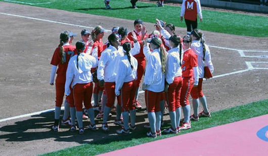 Members of the OSU softball team huddle outside the dugout during a game against Maryland. Credit: Lantern File Photo