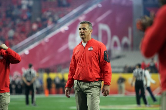 OSU coach Urban Meyer stands in a crowd of reporters after the Fiesta Bowl against Notre Dame on Jan. 1 at University of Phoenix Stadium in Glendale, Arizona. OSU won 44-28.  Credit: Samantha Hollingshead | Photo Editor 