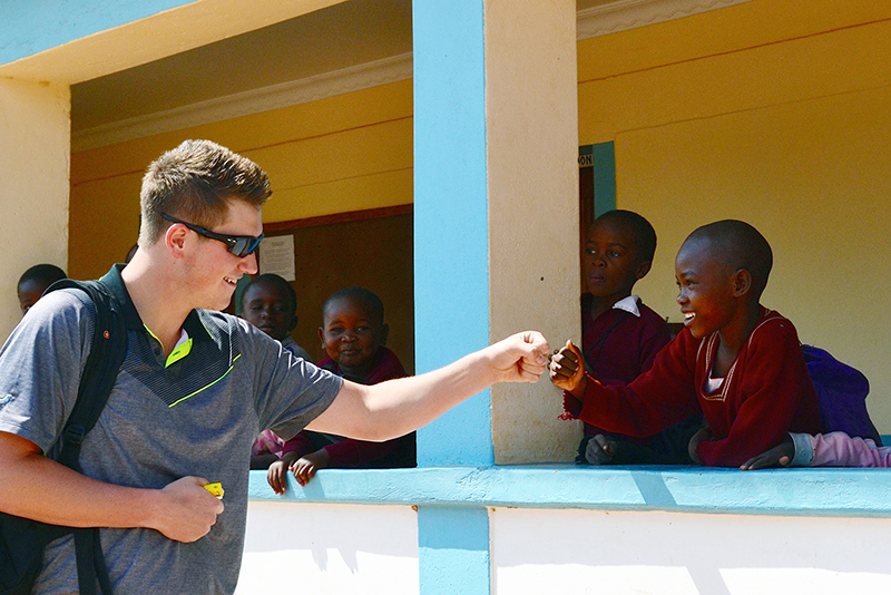 Tyler Pica, a 2015 Ohio State graduate in civil engineering, fist-bumps with a Tanzanian child during an August 2015 visit to several rural Tanzanian villages as part of an engineering capstone trip co-sponsored by the Global Water Institute. Credit: Courtesy of Michael Hagenberger