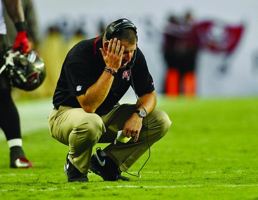 Then-Tampa Bay Buccaneers head coach Greg Schiano crouches on the field during a time out on Sept.15, 2013, in Tampa, Florida | Courtesy of TNS