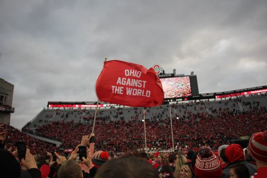 Fans wave a flag on the field after the Buckeyes' game against Michigan on Nov. 26 at Ohio Stadium. The Buckeyes won 30-27. Credit: Mason Swires | Assistant Photo Editor