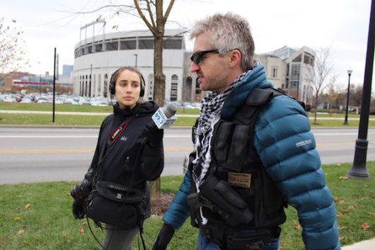 An open-carrying protester speaks with a WOSU reporter while walking past The 'Shoe on Dec. 5.Credit: Nick Roll | Campus Editor